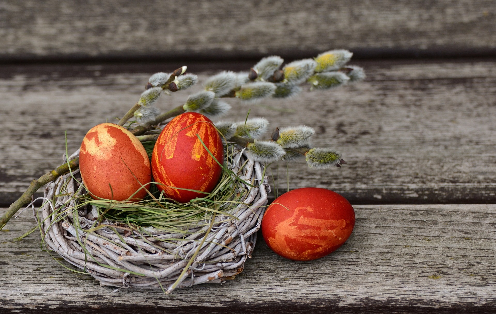Drei Ostereier liegen auf einem Nest. Die Ostereier sind rötlich gefärbt.